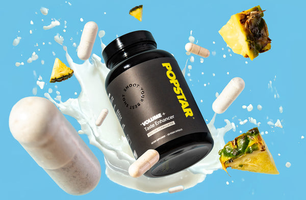 Black supplement bottle labeled 'Popstar' with pineapple slices and white capsules on a blue background